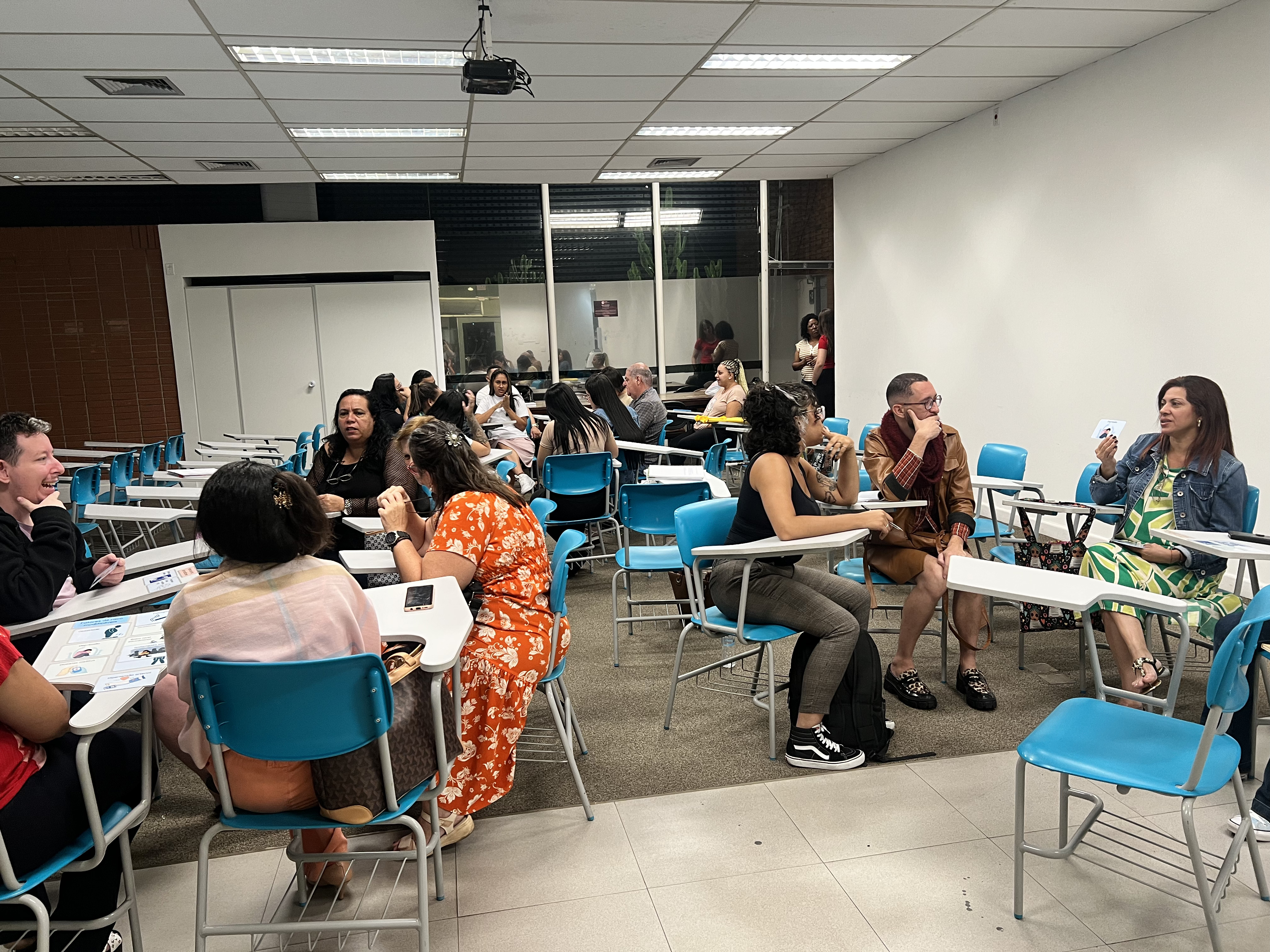 24/01/2025 - Aula do curso piloto do EnvelheCiência, no MOVA, na cidade de São Carlos. Aula proferida pela professora Márcia Cominetti e professora Lea Veras, com apoio técnico das gerontólogas Karen Pulgatti e Letícia Palma. Na imagem vemos, através da câmera que grava a apresentação, presa em um tripé, a professora Márcia Cominetti apresentando sua palestra, com a imagem do ator Michael J. Fox.